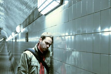 sad looking man leaning against wall in subway